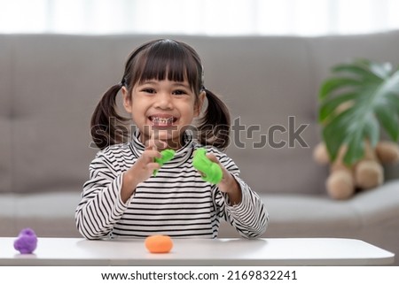 The little girl is learning to use colorful play dough in a well lit room 