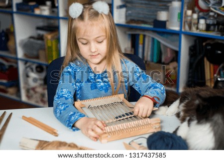A little girl learns process to weave thick threads