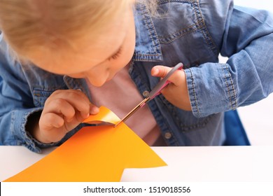 Little Girl Left-handed Cutting Construction Paper At Table, Closeup