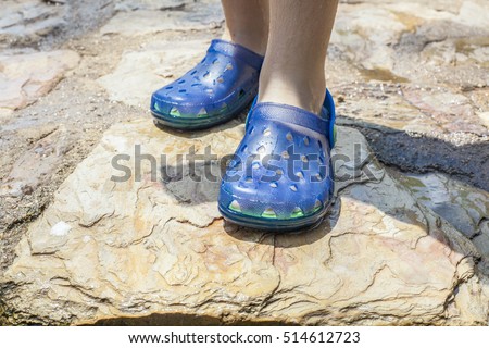 Little girl legs wearing her blue plastic clogs just after swimming
