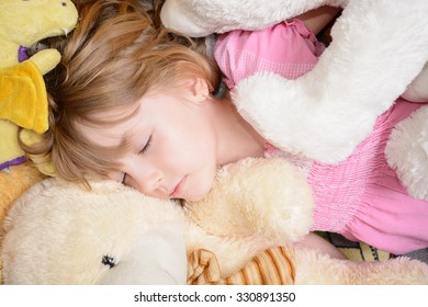 Little Girl Lies Among Stuffed Animals And Sleeping