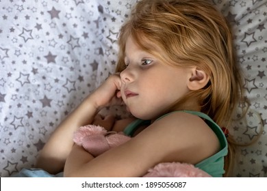 A Little Girl Lies Under A Blanket With A Toy Dog Getting Ready For Bed