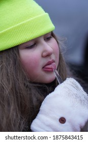 Little Girl With Long Hair Licking Frozen Icicle. Selective Focus.