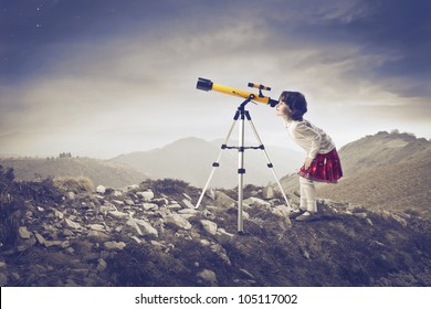 Little girl looking into a telescope in the mountains