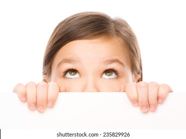 Little girl is looking from out blank board, isolated over white