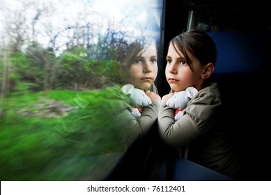 Little girl looking through window. She travels on a train.