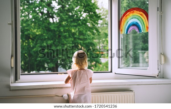 春の時 小さな女の子は開いた窓の外を見る 窓に虹を描く 緑の木を背景に部屋の窓を開く 子供は家で暇です 検疫中のサポート 新鮮な空気を感じる の写真素材 今すぐ編集