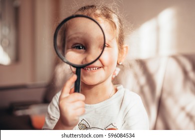 Little girl looks through a magnifier