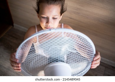 A Little Girl Looks Towards A Large Fan, Hides Behind It And Enjoys The Breeze In The Heat, She Is Blown Away By Wind Currents.