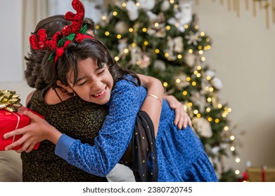 Little girl lovingly hugs her mother at Christmas dinner. - Powered by Shutterstock