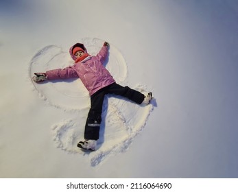 Little Girl Lying In Snow And Making Angel Top View