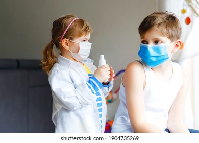 Little Girl Makes Injection To Brother, School Kid Boy. Children, Siblings With Medical Mask Playing Doctor, Holding Syringe With Vaccine. Coronavirus Covid Vaccination Concept. Kids Play Role Game