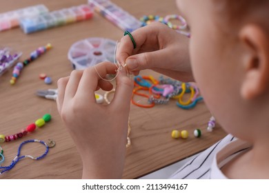 Little Girl Making Beaded Jewelry At Table, Closeup