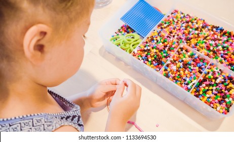 Little Girl Making Bracelet From Colorful Kids Beads.