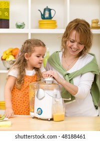 Little Girl Making Fresh Fruit Juice With Her Mother Using A Kitchen Appliance