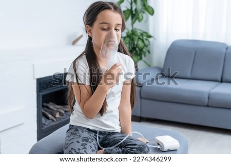 Little girl making inhalation with nebulizer at home. child asthma inhaler inhalation nebulizer steam sick cough concept.