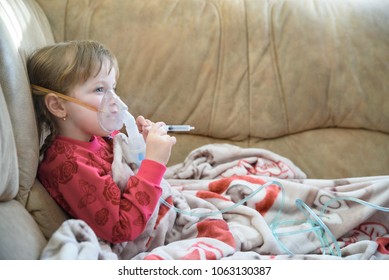 Little girl in a mask, cough treatment using a nebulizer at home