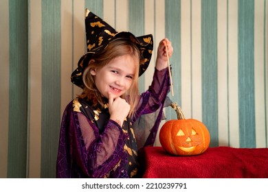 A Little Girl In A Masquerade Witch Costume With A Pumpkin Lantern For Halloween. The Tradition Of Dressing Up And Making Decorations For Halloween.