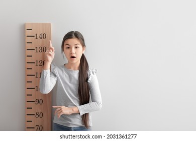 Little Girl Measuring Height Near Light Wall