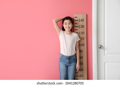 Little Girl Measuring Height Near Color Wall