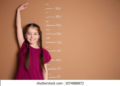 Little Girl Measuring Her Height On Color Background