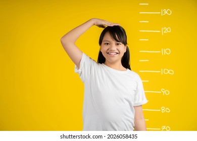 Little girl measuring her height on color background.