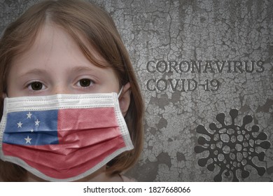 Little Girl In Medical Mask With Flag Of Samoa Stands Near The Old Vintage Wall With Text Coronavirus, Covid, And Virus Picture. Stop Virus