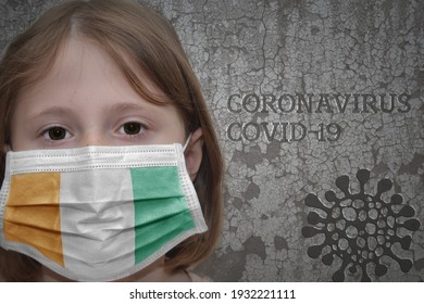 Little girl in medical mask with flag of cote divoire stands near the old vintage wall with text coronavirus, covid, and virus picture. Stop virus