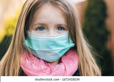 A Little Girl In A Medical Mask With Sad Eyes And Hope. Coronavirus Covid-19 Concept. Close-up