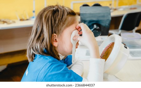 Little girl in medical office undergoing advanced laser vision treatment, correction for eyes health. Pediatric ophthalmology procedure. Visual acuity, strabismus improvement. Advanced technology. - Powered by Shutterstock