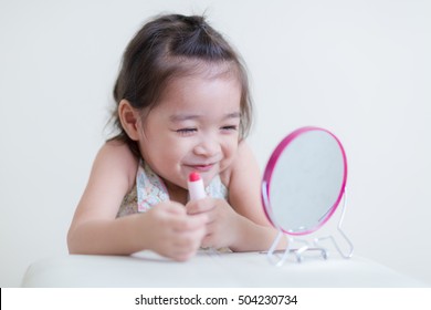 Little Girl With Mirror Doing Makeup At Her House