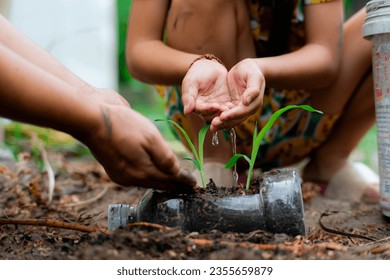 Little girl and mom grow plants in pots from recycled water bottles in the backyard. Recycle water bottle pot, gardening activities for children. Recycling of plastic waste - Powered by Shutterstock