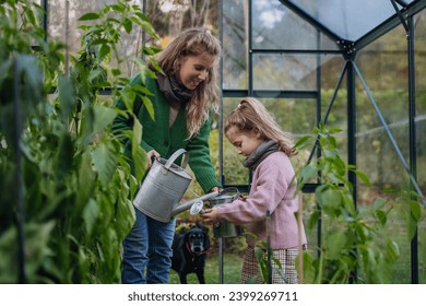 Little girl and mother watering plants in garden, using collected rainwater. Concept of water conservation in garden and family gardening. - Powered by Shutterstock