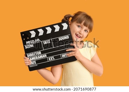 Little girl with movie clapper on color background