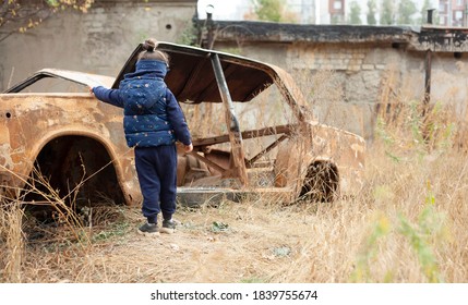 Little girl near the burned-out car. War in Donetsk. War Nagorno-Karabakh. Burned-out car. - Shutterstock ID 1839755674