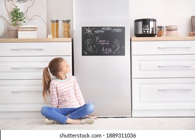 Little girl near chalkboard on refrigerator in kitchen - Powered by Shutterstock