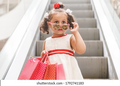 little girl on the escalator in the mall with colored bags
