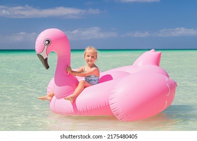 Little Girl On Inflatable Flamingo On The Sea. Travel Lifestyle, Swimming Activities In Family Summer Camp. Summer Vacations 2020 On Tropical Island After Coronavirus Covid-19 Lockdown Concept