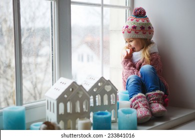 little girl on a window sill looks at the street