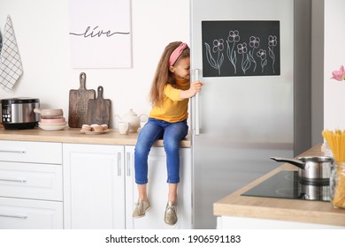 Little Girl Opening Refrigerator In Kitchen