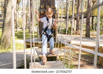 Little girl overcomes the obstacle in the rope park. cute girl runs track, leisure on nature. - Powered by Shutterstock