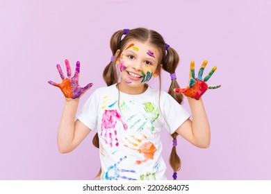 A little girl painted with multicolored paints will playfully have to create on a pink isolated background. Development of children's creativity for schoolchildren. - Powered by Shutterstock