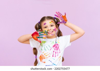 A little girl painted with multicolored paints will playfully have to create on a pink isolated background. Development of children's creativity for schoolchildren. - Powered by Shutterstock