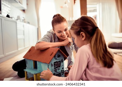 Little girl painting a doll house with her mother at home - Powered by Shutterstock