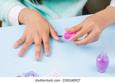 Little Girl Painting Her Nails At Home With Clear Varnish