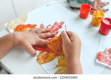 Little girl painting on autumn yellow leaves with gouache, kids arts, children creativity, autumn art. - Shutterstock ID 2354053481