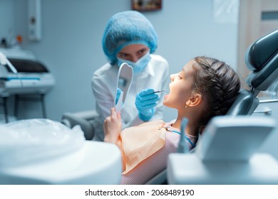 Little girl patient and dentist are checking teeth at mirror after dental treatment in dental office. Dentistry concept  - Powered by Shutterstock