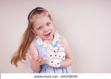 Little Girl With A Piggy Bank. Child Emotions And Money Theme. Photo Taken On A Light Isolated Background, Straight View.