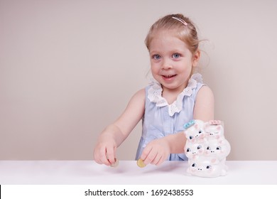 Little Girl With A Piggy Bank. Child Emotions And Money Theme. Photo Taken On A Light Isolated Background, Straight View.