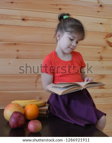 a little girl in a pink dress enjoys reading interesting books